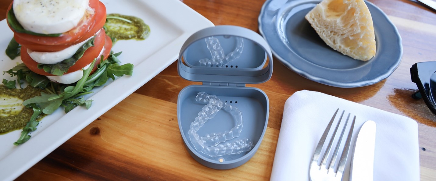 SPARK clear aligners sitting in a case with the lid open on a table with food.